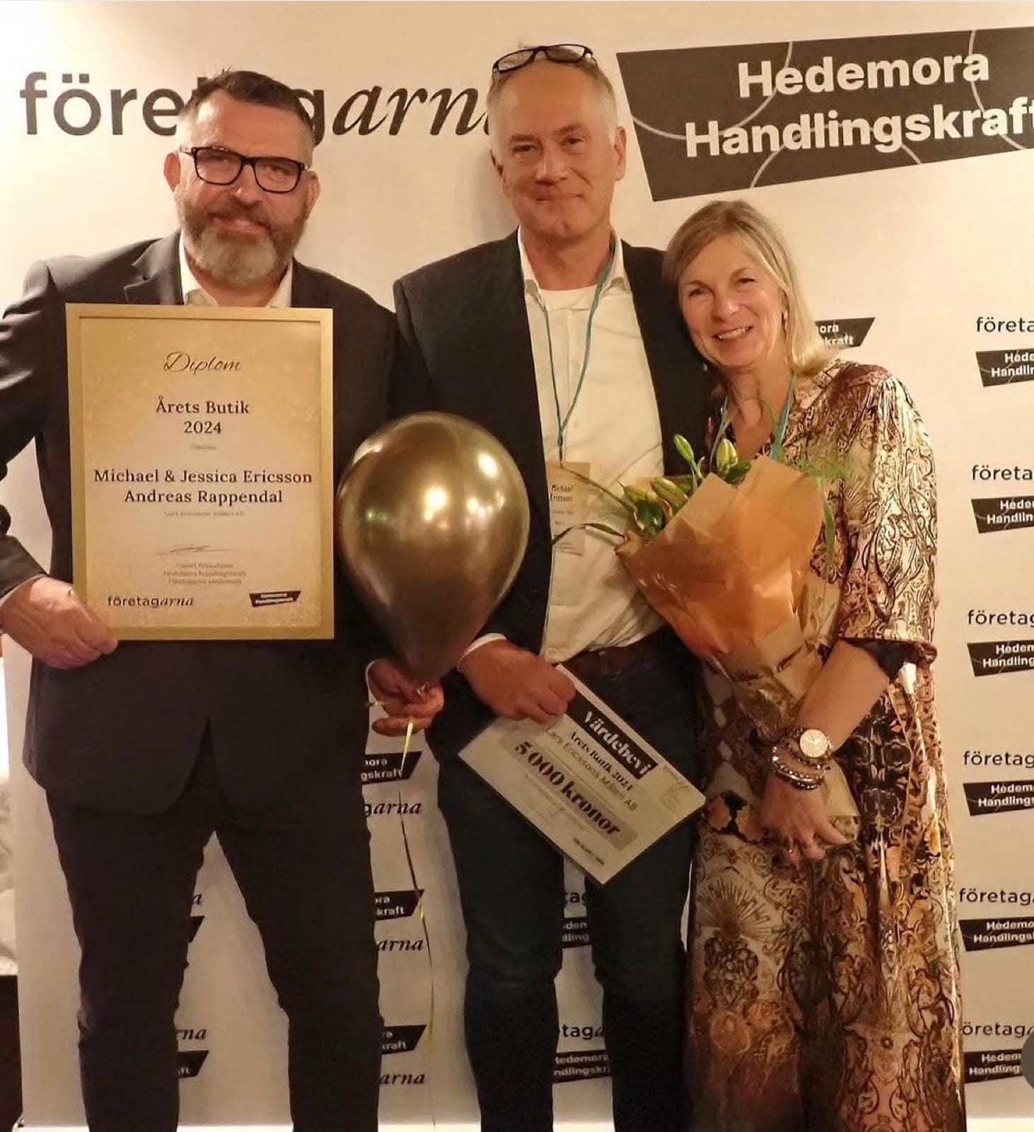 Tre pristagare med diplom och blommor framför Företagarnas prisvägg